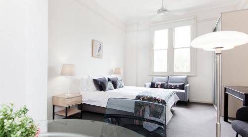 悉尼Excelsior Apartments at Glebe的白色卧室配有床和玻璃桌