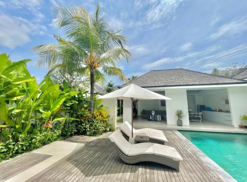 塞米亚克Alami Luxury Villa的一座房子旁的游泳池,配有两把椅子和一把遮阳伞