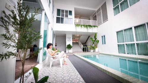 芭堤雅市中心The Inn10 Pool Villa Pattaya, Entire Villa, 9 Bedrooms, Private Indoor Swimming Pool, ดิ อินน์เท็น的坐在游泳池旁椅子上的女人