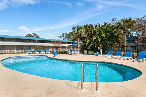 代托纳海滩Baymont by Wyndham Daytona Beach - Intl Speedway的一座带蓝色椅子的游泳池和一座建筑