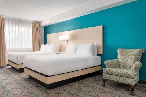 米拉米契Ramada by Wyndham Miramichi New Brunswick的酒店客房,配有两张床和椅子