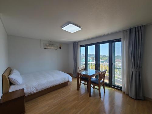 西归浦市赫拉卡斯尔度假屋的一间卧室配有一张床、一张桌子和一个窗户。