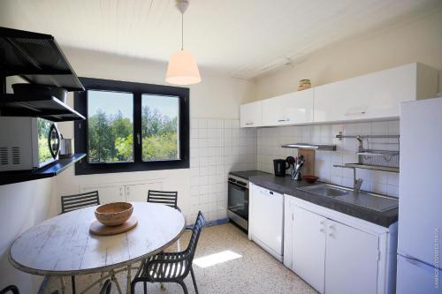 尼姆Maison dans les Arbres, SPA, Tennis, Parking的厨房配有桌椅和窗户。