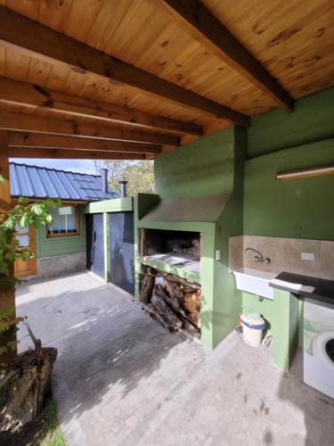 圣马丁德洛斯Cabaña Honey的室外厨房设有绿色的墙壁和壁炉。