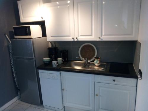 特雷沃 - 特雷吉涅克Maisonnette VUE MER PANORAMIQUE Trestel plage 4 personnes的厨房配有白色橱柜、水槽和冰箱。