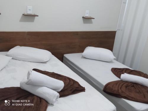 阿帕雷西达Pousada Quarto com ventilador,ar frigobar e garagem的配有2张床的带白色床单和枕头的客房