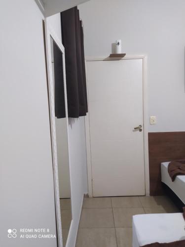 阿帕雷西达Pousada Quarto com ventilador,ar frigobar e garagem的一间设有白色门和一张床的房间