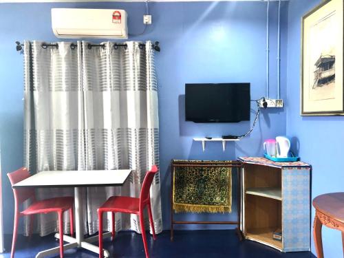 珍南海滩WAN'S ROOMSTAY LANGKAWI的蓝色的客房配有桌椅和电视。