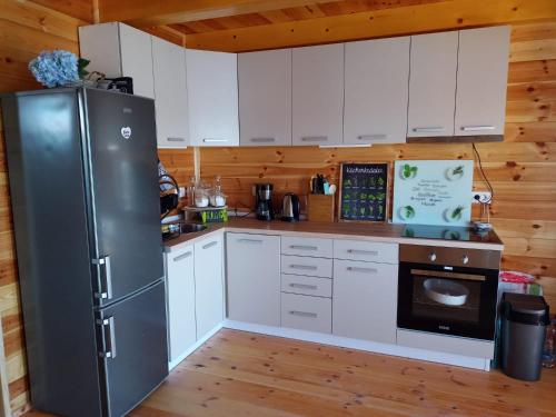 Gornji ŠtojHouse ThoNi的厨房配有白色橱柜和黑色冰箱。