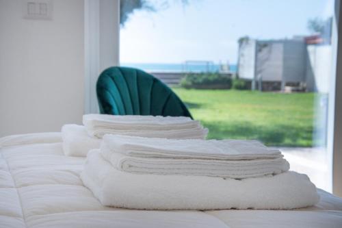 泰拉奇纳Villa degli Squali Suite Home的床上的毛巾堆和绿色椅子