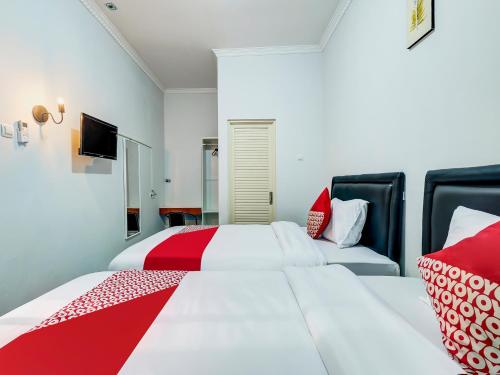 日惹Super OYO Capital O 90983 Harmony Easy Stay的一间卧室配有两张带红白色枕头的床