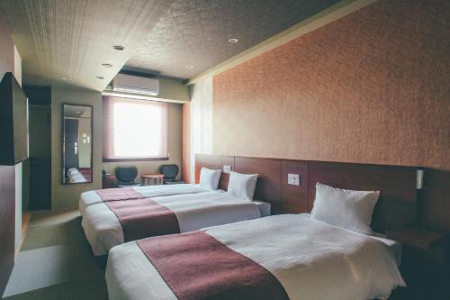 高山Hotel Kuretakeso Takayama Ekimae的酒店客房设有两张床和窗户。