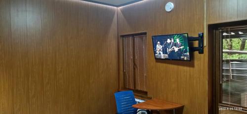 阿拉木图Apartment in a guest house的一间墙上配有电视和一张桌子的房间
