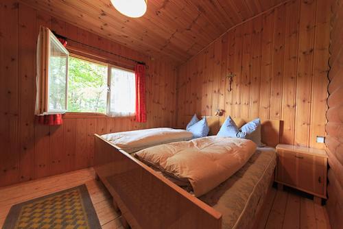 思科纳Aussersalfner Hütte的木制客房内的一间卧室,配有一张床