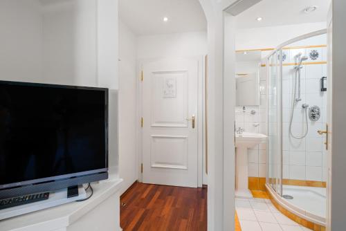 圣加伦基希Hotel Gasthof Adler的带电视的浴室和带淋浴的浴室。