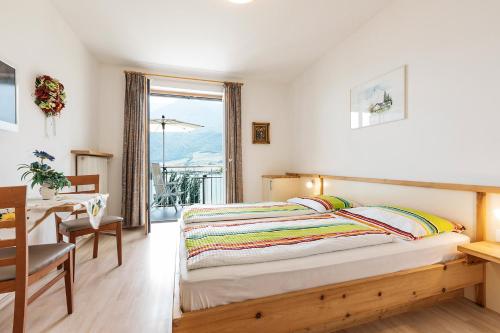 卡尔达罗Appartement Florian的一间卧室配有一张床、一张桌子和一个窗户。