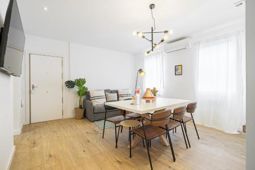 马德里Vallecano Apartments by Olala Homes的厨房以及带桌椅的起居室。
