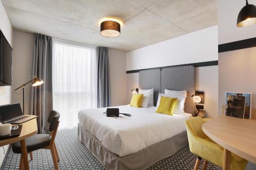 布拉尼亚克Odalys City Toulouse Blagnac Aéroport的酒店客房设有一张大床和一张书桌。