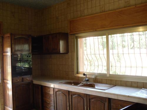梅克内斯VILLA PLAISANCE的厨房配有木制橱柜、水槽和窗户。