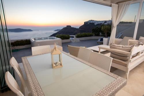 菲罗斯特法尼Sunset View Villa Santorini - with Outdoor Jacuzzi的海景阳台上的桌椅