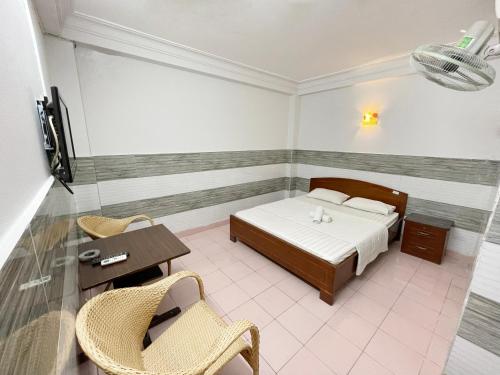 胡志明市Huy Hoàng Hotel的卧室配有一张床和一张桌子及椅子