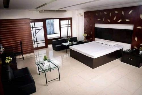 吉大港Hotel Rose Garden的一间卧室配有一张床、一张沙发和一张桌子