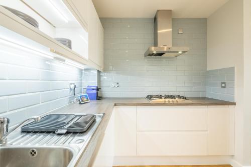 剑桥EXECUTIVE 2BR apartment next to Station + Parking的白色的厨房设有水槽和炉灶。