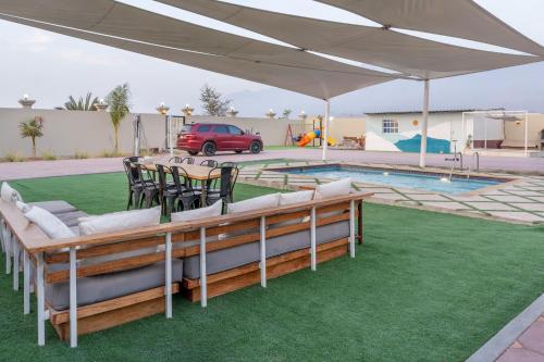 拉斯阿尔卡麦Lazeemah Chalet استراحة اللزيمه的游泳池旁白色天篷下的桌椅