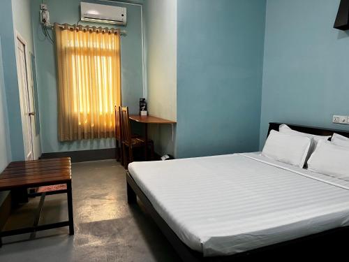 娘瑞旅游之歌旅舍的一间卧室配有一张床、一张桌子和一个窗户。