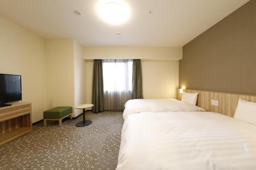 前桥市Dormy Inn Maebashi的酒店客房设有两张床和一台平面电视。