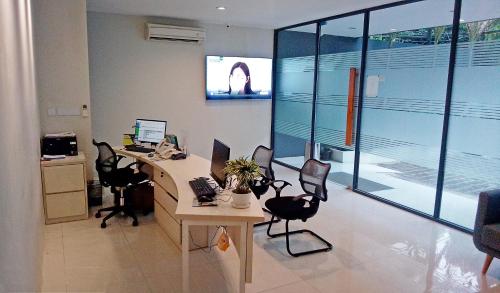 雅加达LeGreen Suite Sudirman的办公室配有桌椅和电脑
