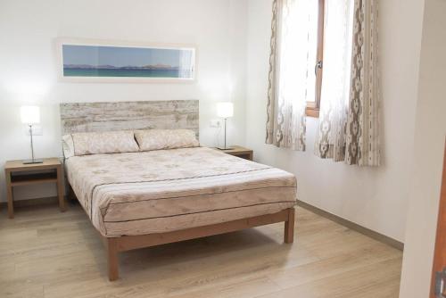 圣玛加利达AGROTURISMO SARAIX的一间卧室配有一张带两张桌子和两盏灯的床。