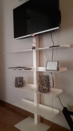 米兰Appartamento Diego的墙上的架子上配有电视