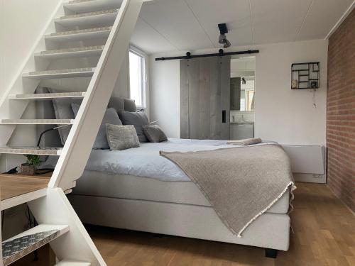 兹瓦茨勒伊斯Logeren bij Grea的卧室配有白色的床和楼梯。
