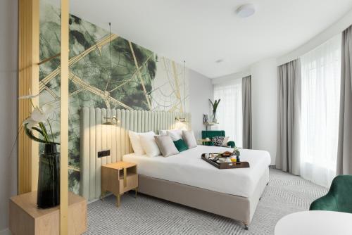 华沙Royal Tulip Warsaw Apartments的卧室配有白色的床和墙上的大画作