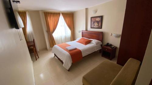 洛哈Hotel Caluva的配有一张床和一把椅子的酒店客房