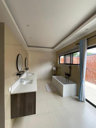 卢萨卡Exclusive Farm Getaway的一间带水槽和浴缸的浴室以及窗户。