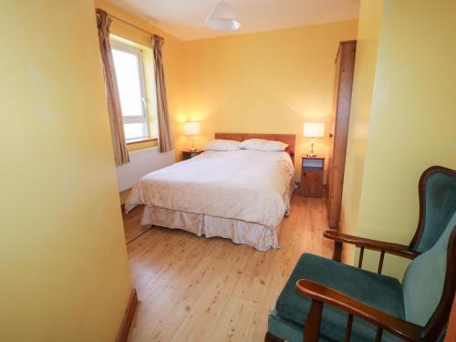邓格洛Carnmore Cottage的卧室配有床、椅子和窗户。