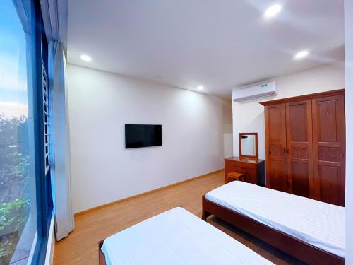 头顿Upla Homestay的一间卧室设有两张床、一台电视和一扇窗户。
