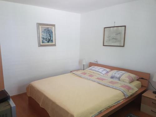 内戈廷Pržić House的卧室内的一张床铺,墙上有两张照片