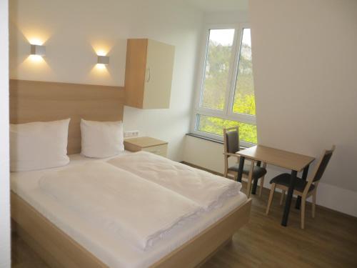 博伊龙Gäste- und Tagungshaus Maria Trost的一间卧室配有一张床、一张桌子和一个窗户。