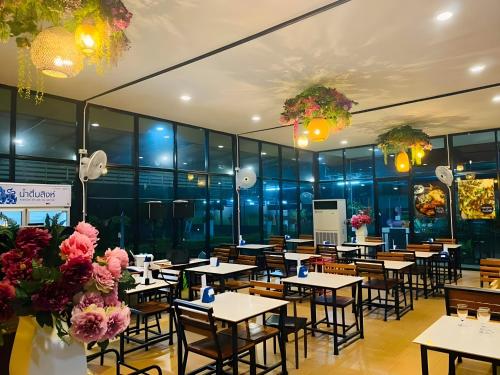 董里Trang Villa Hotel and Water Park的一间带桌椅和鲜花的餐厅