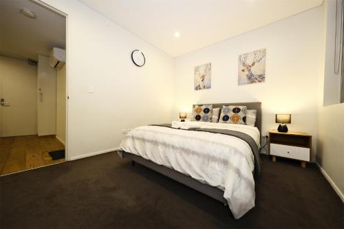 悉尼Superb 1 bed apartment in Syd CBD Darling Harbour的卧室配有一张床,墙上挂着一个钟