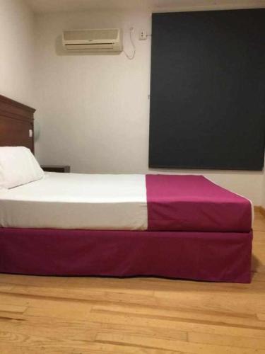 卡塞雷斯KubiK HOTEL的一间卧室配有一张铺有紫色和白色床单的床
