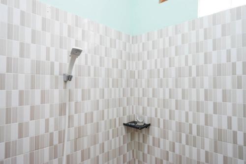 GlagahRedDoorz near Yogyakarta International Airport的浴室内铺有白色瓷砖的淋浴