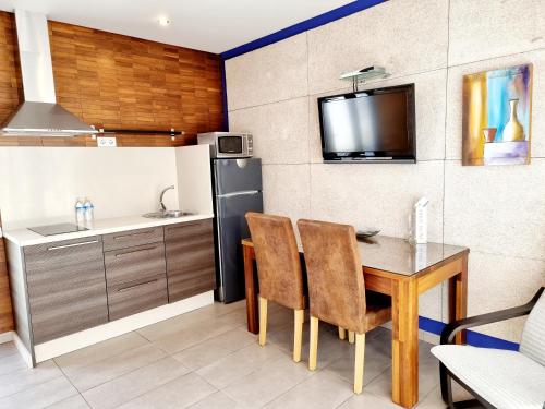 科尼尔-德拉弗龙特拉阿雷西费萨尔瓦多公寓的厨房配有桌椅和冰箱。