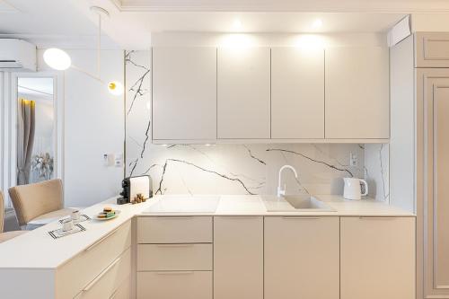 什切齐内克Gold Apartment Szczecinek的白色的厨房配有白色橱柜和水槽