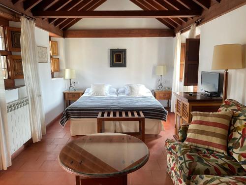 格拉纳达圣伊莎贝尔拉雷亚尔酒店的一间卧室配有一张床、一张桌子和一张沙发