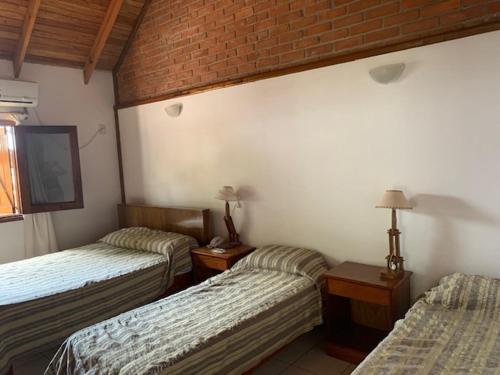 埃尔多拉多Un Lugar Hotel Cabañas的一间设有两张床和砖墙的房间