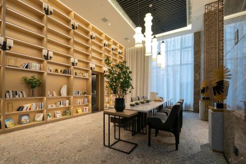 张家界张家界天门山亚朵酒店的图书馆配有桌椅和书架
